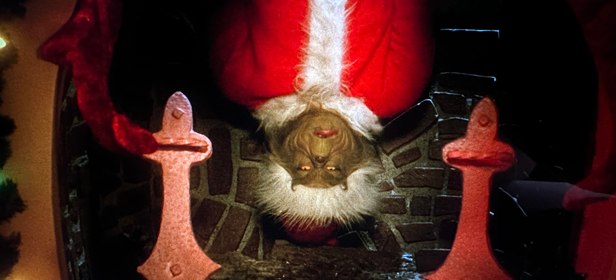 Image of the grinch hanging head first from a fireplace